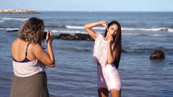 Fotógrafo faz fotos de modelo em vestido rosa contra o mar — Vídeo de Stock