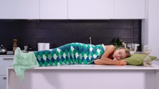 Pretty girl covered with mermaid tail plaid sleeps on table — Stock Video