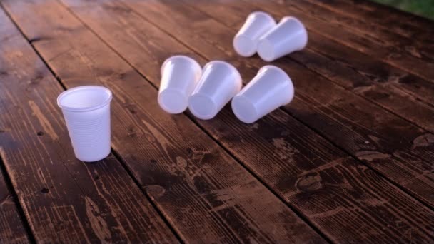 Små engångs vita plastkoppar flyttas med vinden på bordet — Stockvideo