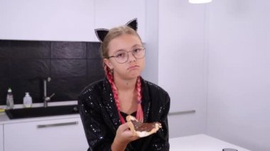 Kedi kulaklı üzgün bir kız çikolata ezmeli sandviç yiyor.