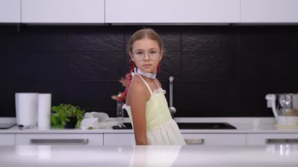 Дівчина в окулярах показує свіжу грушу і яблуко на кухні — стокове відео