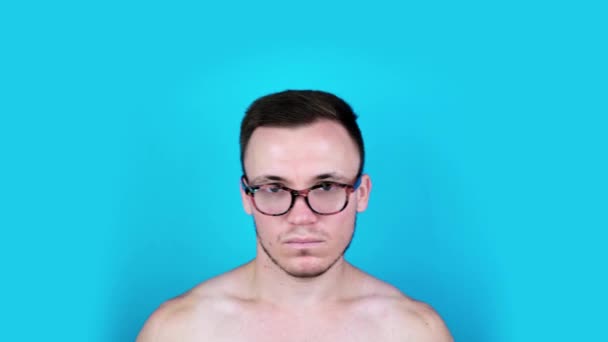 Barbudo hombre con hombros desnudos y gafas sacude la cabeza — Vídeo de stock
