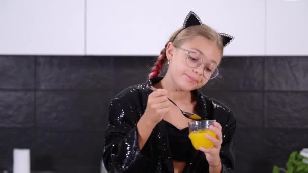 Funny girl dans une veste brillante prend jus de verre avec cuillère — Video