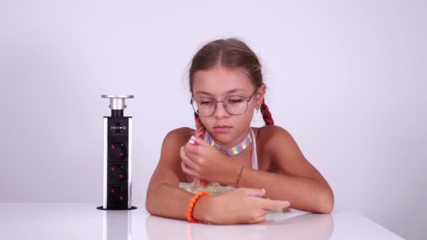 Girl with red blinking eyes charges playing robot in room — Stock Video