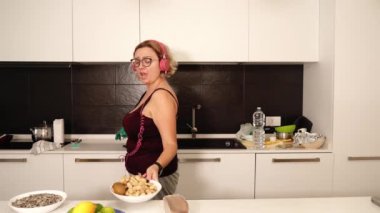 Kıvırcık saçlı neşeli tombul bayan yemek hazırlar ve dans eder.