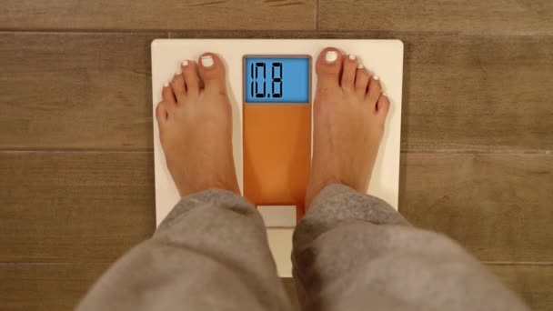 Young woman with white pedicure steps on electronic scales — Stock Video