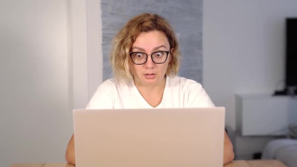 Junge Frau tippt auf weißem Laptop und zieht schockierte Gesichter — Stockvideo