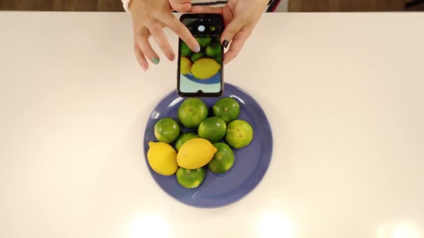 Las manos cuidadas de la mujer sostienen el teléfono inteligente haciendo fotos de frutas — Vídeos de Stock