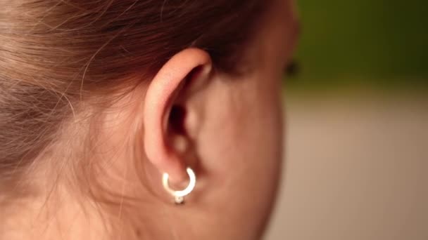 Meisje met lang haar beweegt oor met zilveren oorbel closeup — Stockvideo