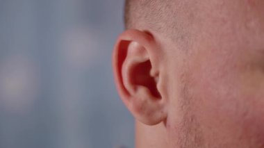 İfade veren kel adam mavi kulakları oynatabildiğini gösteriyor.