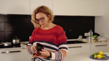 Kadın kırık akıllı telefonu sallayıp beyaz çöp kutusuna atıyor.