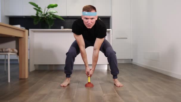 Sportieve man houdt zuiger pompen bruin houten vloer thuis — Stockvideo