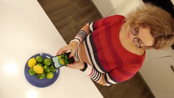 Блондинка в окулярах робить фотографії з купою лимонів — стокове відео