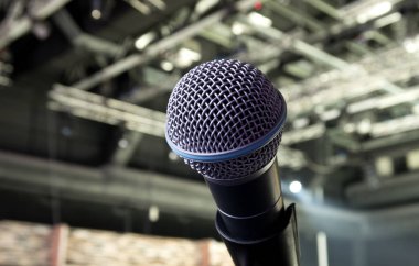 Sahne Alanı'nda dinamik bir mikrofon. Arka plandaki parlak spot ışığı.