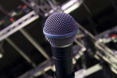 Sahne Alanı'nda dinamik bir mikrofon. Arka plandaki parlak spot ışığı.