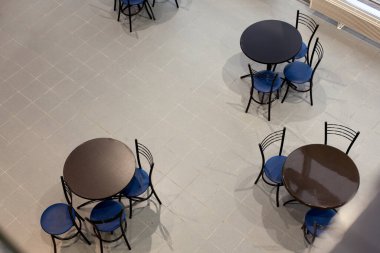Yuvarlak masalar ve sandalyeler boş kafenin iç tarafında, üst tarafta.