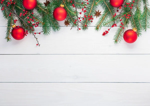 Noel arka plan ile çam dalları ve kırmızı Noel topları, berberis dalları ile meyve ve anasonu Beyaz ahşap zemin üzerinde