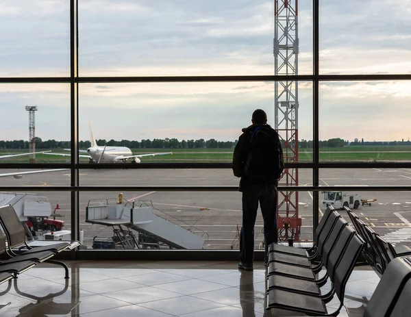 Sırt çantası olan adam uçaklara bakıyor.