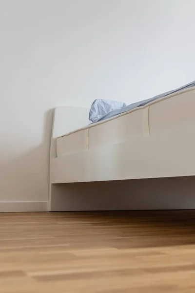 White bed with mattress and blue linens