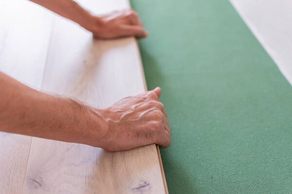 Worker installing wooden laminate flooring
