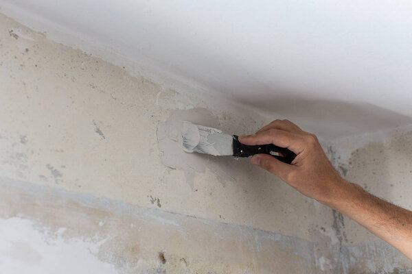 Worker's hand with a spatula and putty