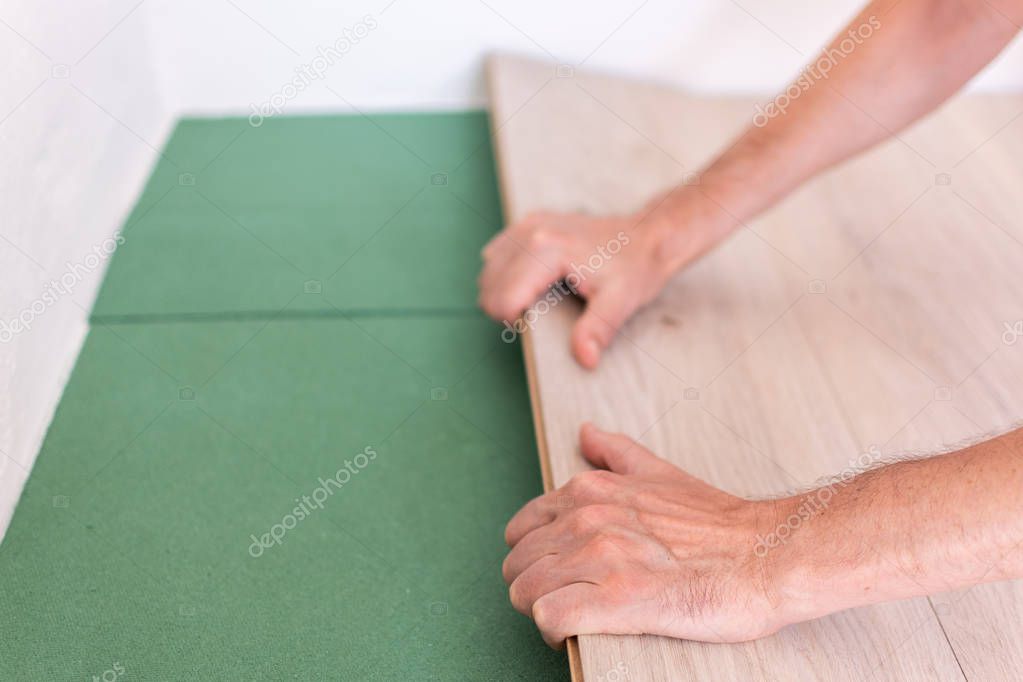 Worker installing wooden laminate flooring