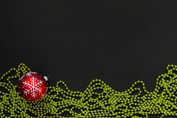 Рождественский бал и бусы на черном фоне — стоковое фото