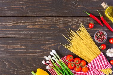 Çiğ spagetti, taze, sulu sebzeler ve ahşap arka planda baharatlı zeytinyağı.