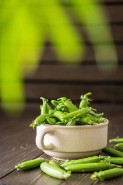 Derin seramik tabakta taze taze taze bezelyeler, olgun organik sebzeler.