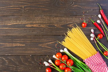 Çiğ spagetti, taze olgun meyve suyu ve ahşap arka planda baharatlar.