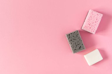 Pembe arka planda sabunlu çok renkli temizlik süngeri, temizlik ve temizlik konsepti.