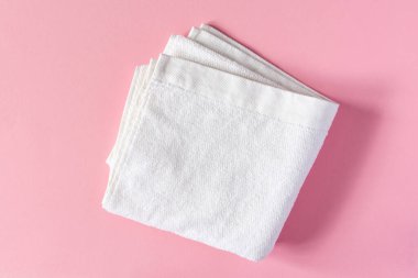 Pembe arka planda beyaz havlu, banyo aksesuarları.