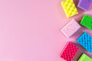 Pembe arka planda çok renkli temizlik süngeri, temizlik ve temizlik konsepti