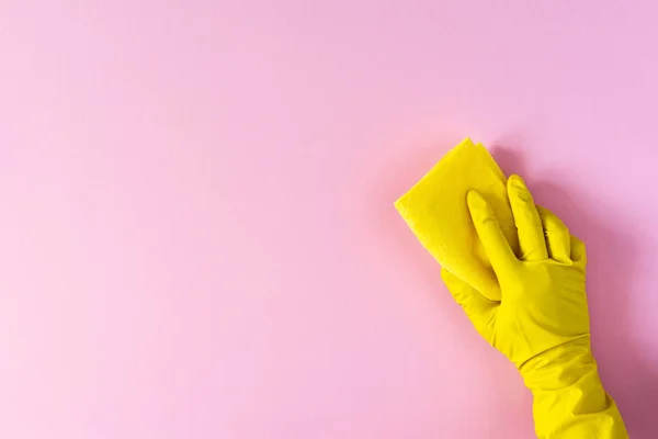 交一只黄色的橡胶手套 上面有粉红背景的清洁海绵 — 图库照片