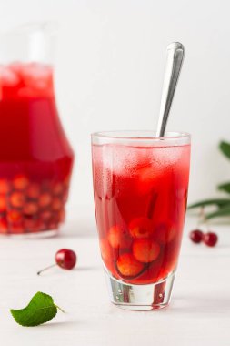 Yaz mevsimi ferahlatıcı kiraz kompostosu hamurlu ve beyaz arka planda buzlu bardaklar, bir sürahi içkili.