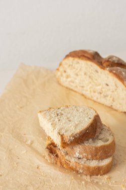 Bir somun ev yapımı ekmek dilimlenmiş ekmek ve parşömen kağıdında tohum.