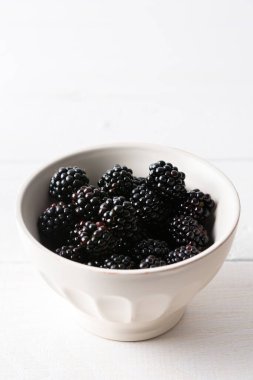 Böğürtlenler, beyaz arka planda, olgun meyveler üzerinde kaseler halinde.