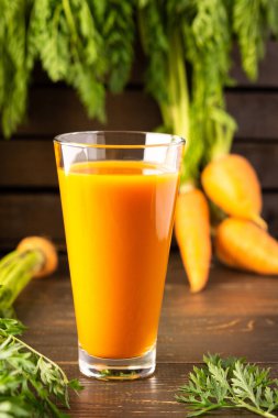 Tahta bir masada şekersiz gözlüklü doğal havuç suyu.