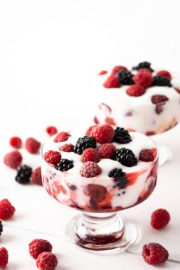 Lezzetli ahududu ve böğürtlen böğürtlenleri beyaz arka planda cam bir formda yoğurt ile