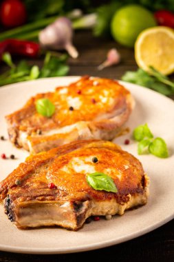 Kemikte kızarmış domuz eti, fesleğen yaprağı ve baharatla pişirilmiş domuz eti, ahşap bir arka planda, kemikte biftek.