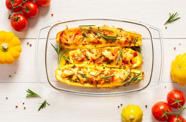 Stewed yellow zucchini with tomatoes and onions, cheese and herbs, carrots and spices, stuffed zucchini on a white wooden background