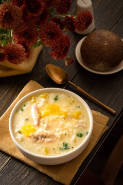 Kaşık içinde tavuk, pirinç ve balkabağı çorbası, lezzetli öğle yemeği veya kahvaltı, vazoda çiçekler, ekmek ve balkabağı.