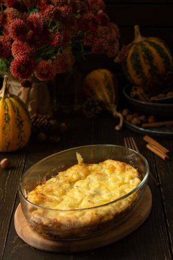 Mozzarella soslu kabaklı frittata, ahşap arka planda fırında peynirle pişirilmiş cam tabakta omlet.