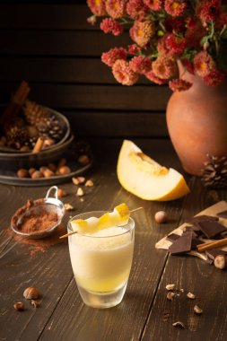 Tarçınlı, fındıklı ve çikolatalı nefis kavun püresi, kasımpatı vazosu ve ahşap arka planda bir bardak smoothie.