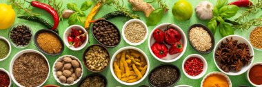 Renkli baharatlar ve bitkiler narin yeşil bir arka planda sergilenmiş, canlı doğal bir görünüş için tazeliklerini ve kokularını vurguluyorlar.
