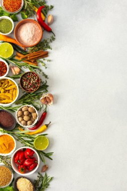 Tarafsız gri bir zemine yayılmış çeşitli baharatlar ve otlar zengin, doğal tonlarını, üst görüntülerini, kopyalama alanlarını sergiliyor.