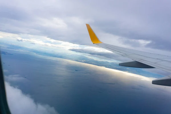 Pandangan udara langit biru dan awan terlihat melalui jendela pesawat, sayap pesawat dari jendela . — Stok Foto