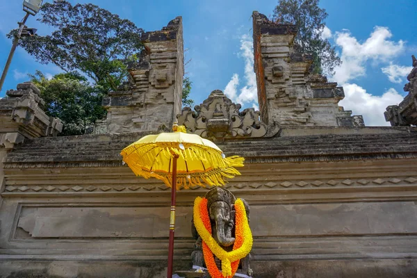 Big statue of Ganesha with yellow flowers necklace and umbrella