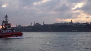 Tarihi yarımadanın siluetleri, yavaş hareket halinde uçan martılar ile yolcu gemileri ve Boğaz'ın girişi, Karaköy'den dramatik gökyüzü ve bulutlar üzerinde manzara, İstanbul