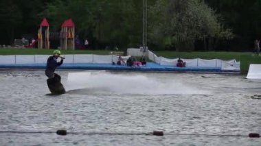 Moskova, Rusya, 06 Temmuz 2019: Beyaz genç adam şehir gölünde wakeboard üzerinde hileler yapıyor, Rider hileler yapmak için wakeboard rampa kullanarak
